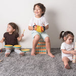 Three children playing Plan Toys musical instrument toys including a concertina