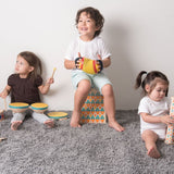 Three children playing Plan Toys musical instrument toys including a concertina