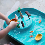 A close up of a child's hand playing with the PlanToys Water Play Set. 