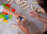 A close up of a child's and adult's hands playing with the PlanToys 40 unit Colourful Block set. 