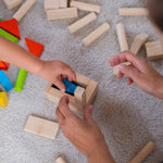 A close up of a child's and adult's hands playing with the PlanToys 40 unit Colourful Block set. 