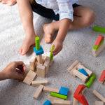 A close up of a child's hand playing with the PlanToys 40 unit Colourful Block set. 