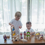 Two children playing with a collection of different PlanToys block sets. They have the PlanToys natural wooden 50 Unit Building Block set along with the castle blocks and water window blocks.