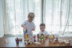 Two children playing with a collection of different PlanToys block sets. They have the PlanToys natural wooden 50 Unit Building Block set along with the castle blocks and water window blocks.