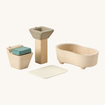A close up view of the PlanToys wooden toilet with the seat down, sink bath and rug that go with the bathroom set
