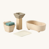 A close up view of the PlanToys wooden toilet with the seat down, sink bath and rug that go with the bathroom set