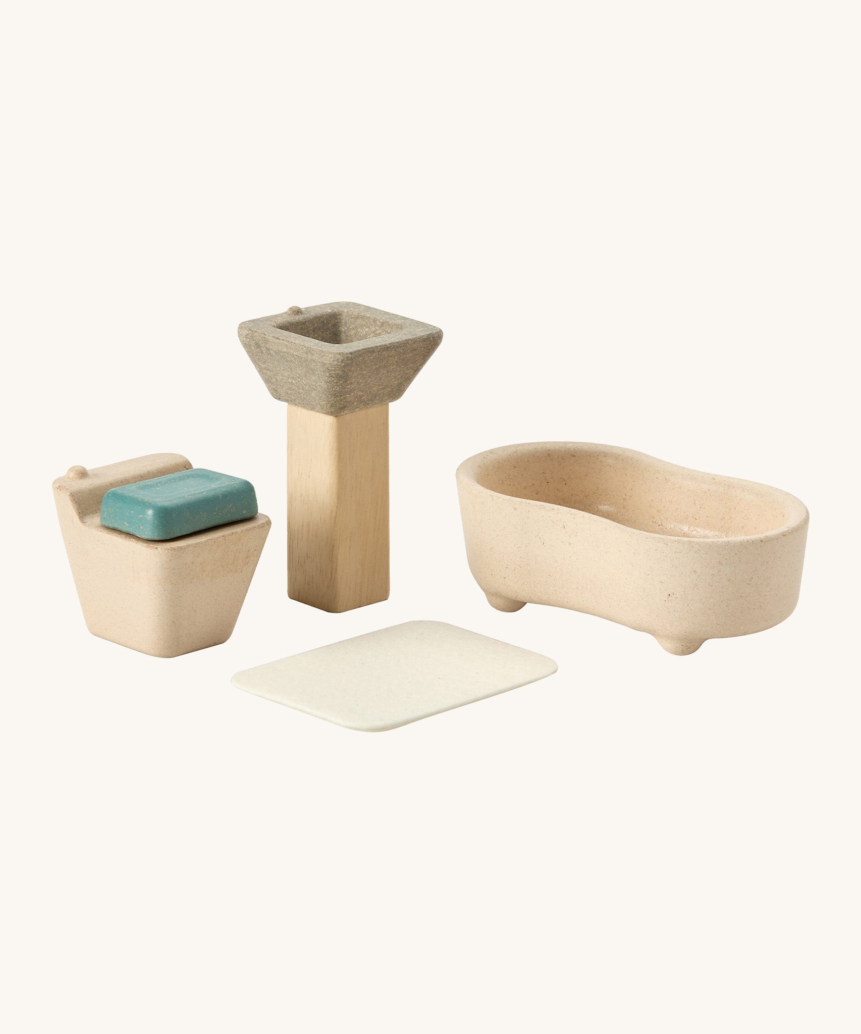A close up view of the PlanToys wooden toilet with the seat down, sink bath and rug that go with the bathroom set