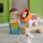 A closeup of the PlanToys wooden dog from the pet shop, with a rubber cone around its neck.