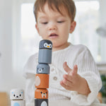A child making a tower with the PlanToys arctic animals matching figures on a white table