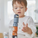 A child making a tower with the PlanToys arctic animals matching figures on a white table