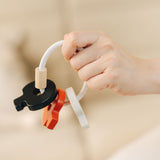 A close up of the PlanToys wooden baby key rattle toy in a high contrast colourway shown in an dult's hand. This baby toy has three wooden keys in white, red and black strung onto a white rope hoop. PlanToys range of toys are made from sustainably sourced rubberwood, we're proud stockists of PlanToys here at Babipur. 