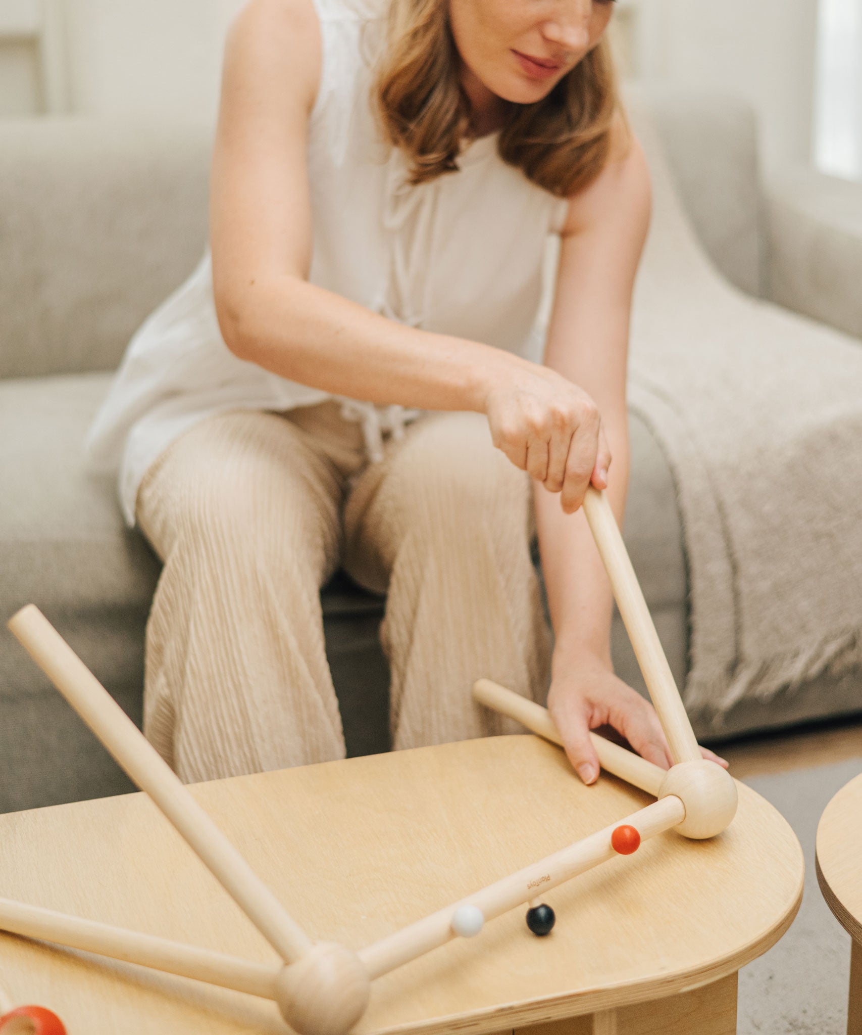An adult assembling the PlanToys High Contrast Wooden Baby Play Gym. This wooden baby gym has high contrast coloured features and detailing. The gym comes with two wooden hanging toys, a planet and a rocket. PlanToys range of toys are made from sustainably sourced rubberwood, we're proud stockists of PlanToys here at Babipur. 