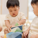 Babies playing with the PlanToys baby tissue box wooden sensory toy.