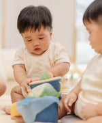 Babies playing with the PlanToys baby tissue box wooden sensory toy.