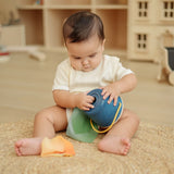 Baby playing with the the PlanToys baby tissue box wooden sensory toy.