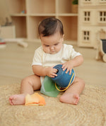 Baby playing with the the PlanToys baby tissue box wooden sensory toy.