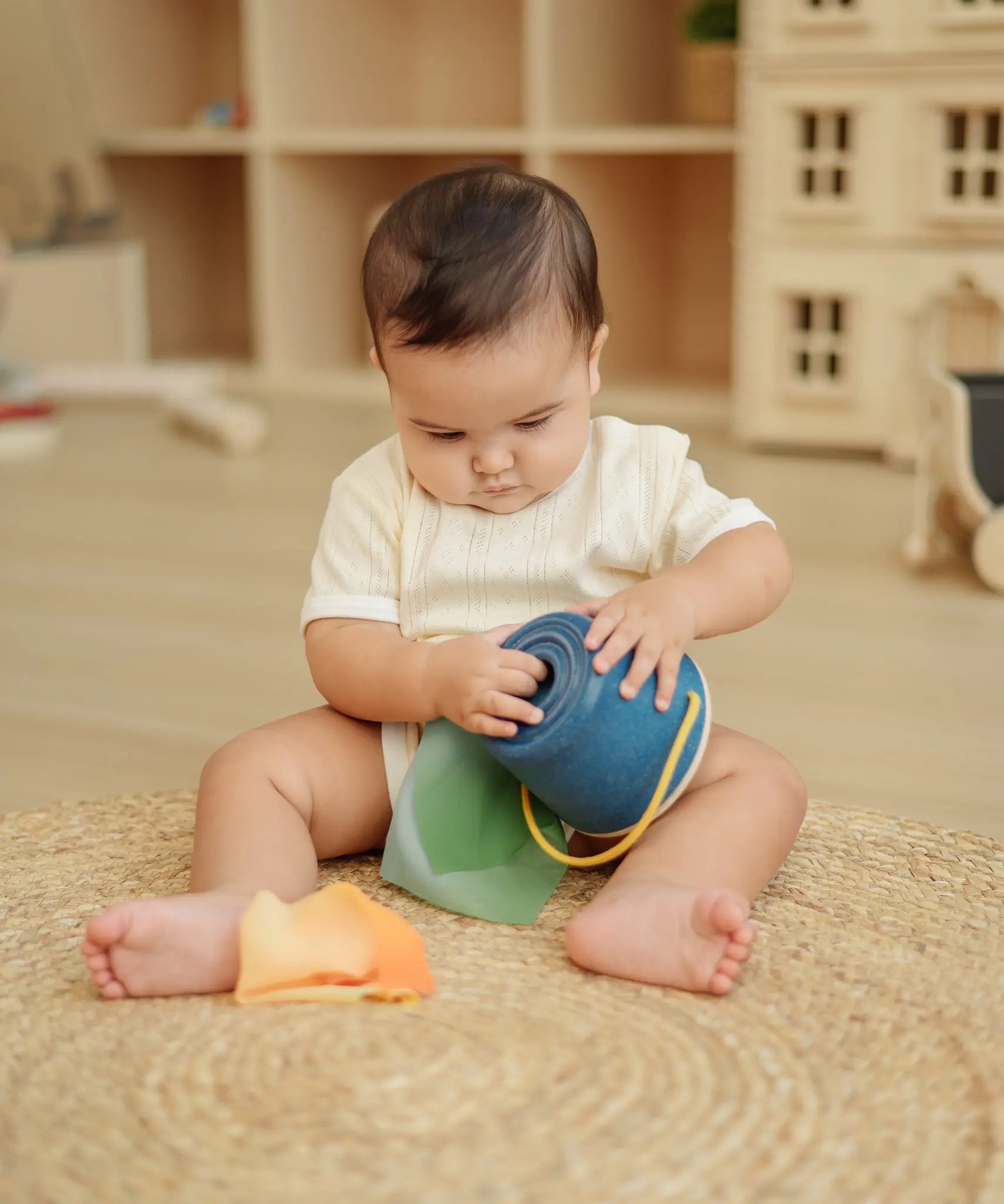 Baby playing with the the PlanToys baby tissue box wooden sensory toy.