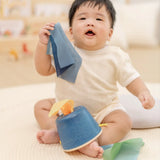 Baby pulling blue material out of the PlanToys baby tissue box wooden sensory toy.