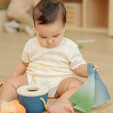 Baby pulling blue material out of the PlanToys baby tissue box wooden sensory toy.