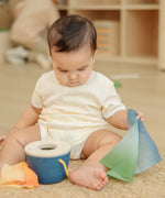 Baby pulling blue material out of the PlanToys baby tissue box wooden sensory toy.