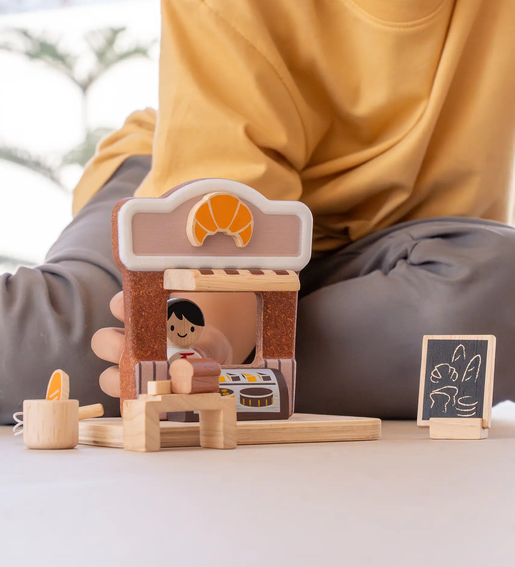 Child playing with the PlanToys bakery shop wooden toy playset.