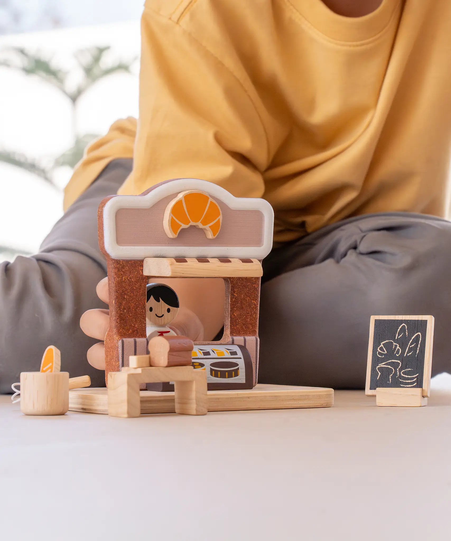 Child playing with the PlanToys bakery shop wooden toy playset.