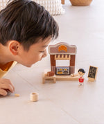 Child playing with the PlanToys bakery shop wooden toy playset.