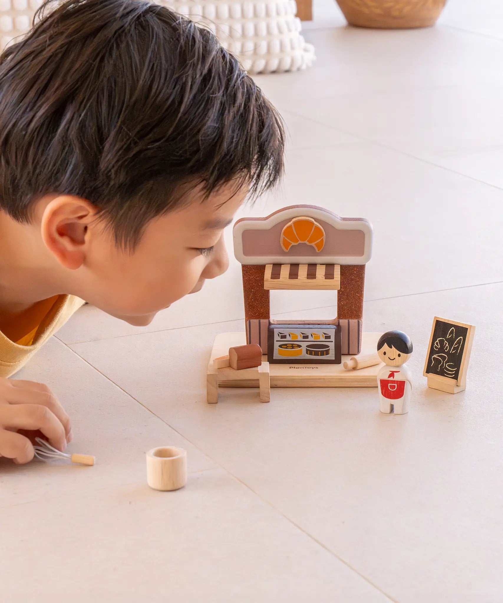 Child playing with the PlanToys bakery shop wooden toy playset.