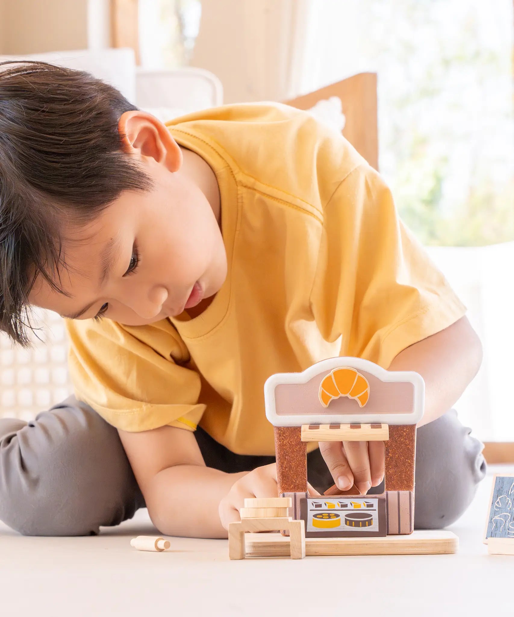 Child playing with the PlanToys bakery shop wooden toy playset.