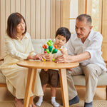 A family of two adults and a child playing with the PlanToys Balancing Cactus. 