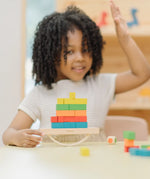 Child playing with the PlanToys balancing cargo wooden balance game. Holding the base piece with a stack of colourful wooden blocks balanced on the base piece.