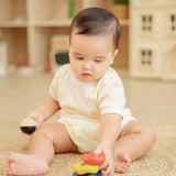 Baby playing with the PlanToys ball and wave stacker wooden baby stacking toy stacking the pieces.