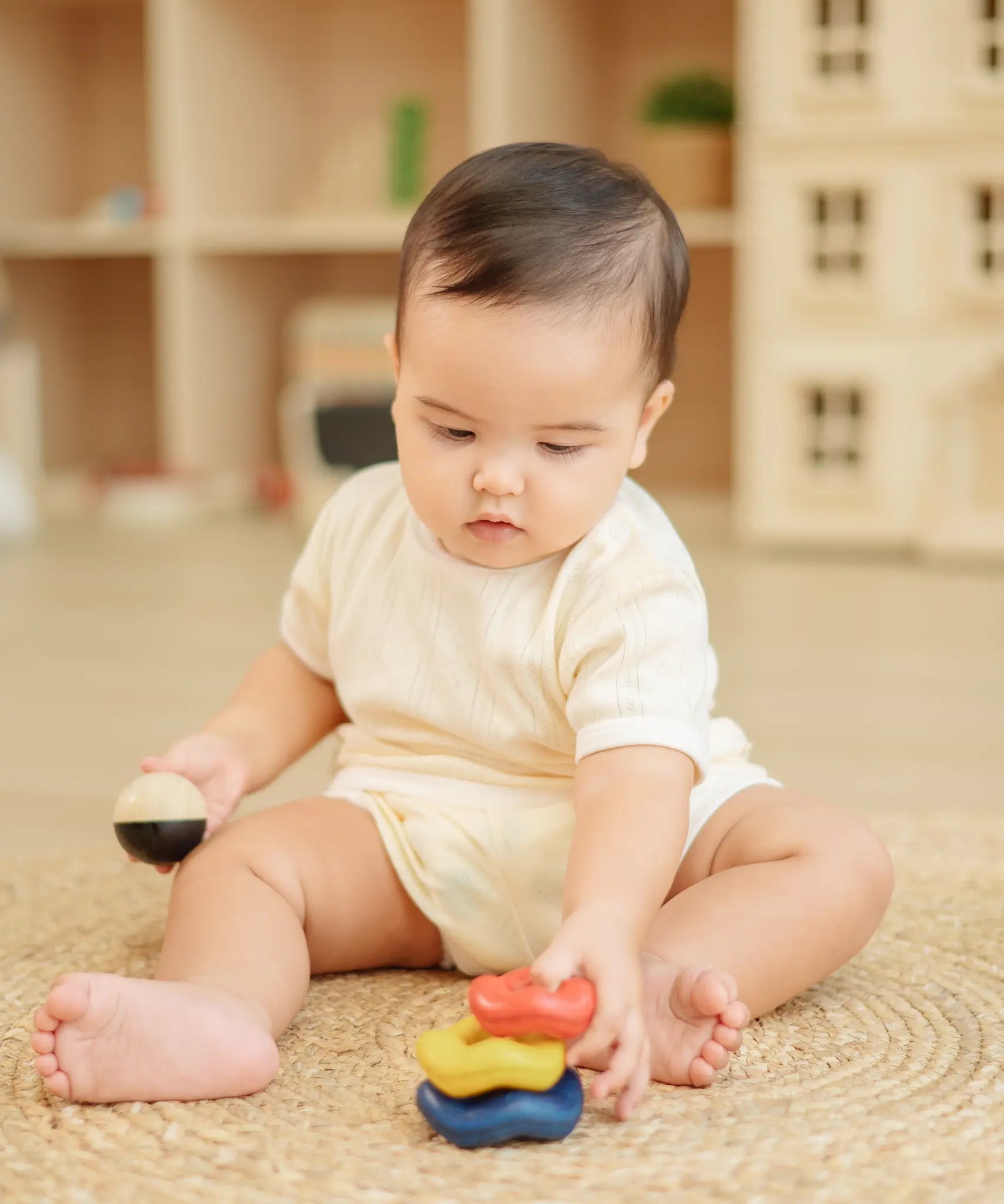 Baby playing with the PlanToys ball and wave stacker wooden baby stacking toy stacking the pieces.