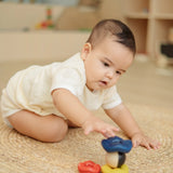 Baby playing with the PlanToys ball and wave stacker wooden baby stacking toy reaching for the stack