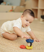 Baby playing with the PlanToys ball and wave stacker wooden baby stacking toy reaching for the stack