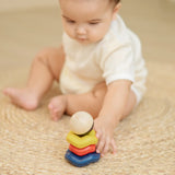 Baby playing with the PlanToys ball and wave stacker wooden baby stacking toy reaching for the stack.