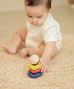 Baby playing with the PlanToys ball and wave stacker wooden baby stacking toy reaching for the stack.