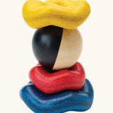 PlanToys wave ball stacker wooden stacking toy. Blue, yellow and red wavy rings with a black and white ball. 