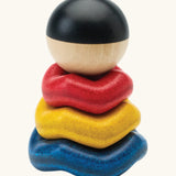 PlanToys wave ball stacker wooden stacking toy. Blue, yellow and red wavy rings with a black and white ball. 