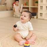 Baby playing with the PlanToys ball and wave stacker wooden baby stacking toy lifting the ball from the stack.