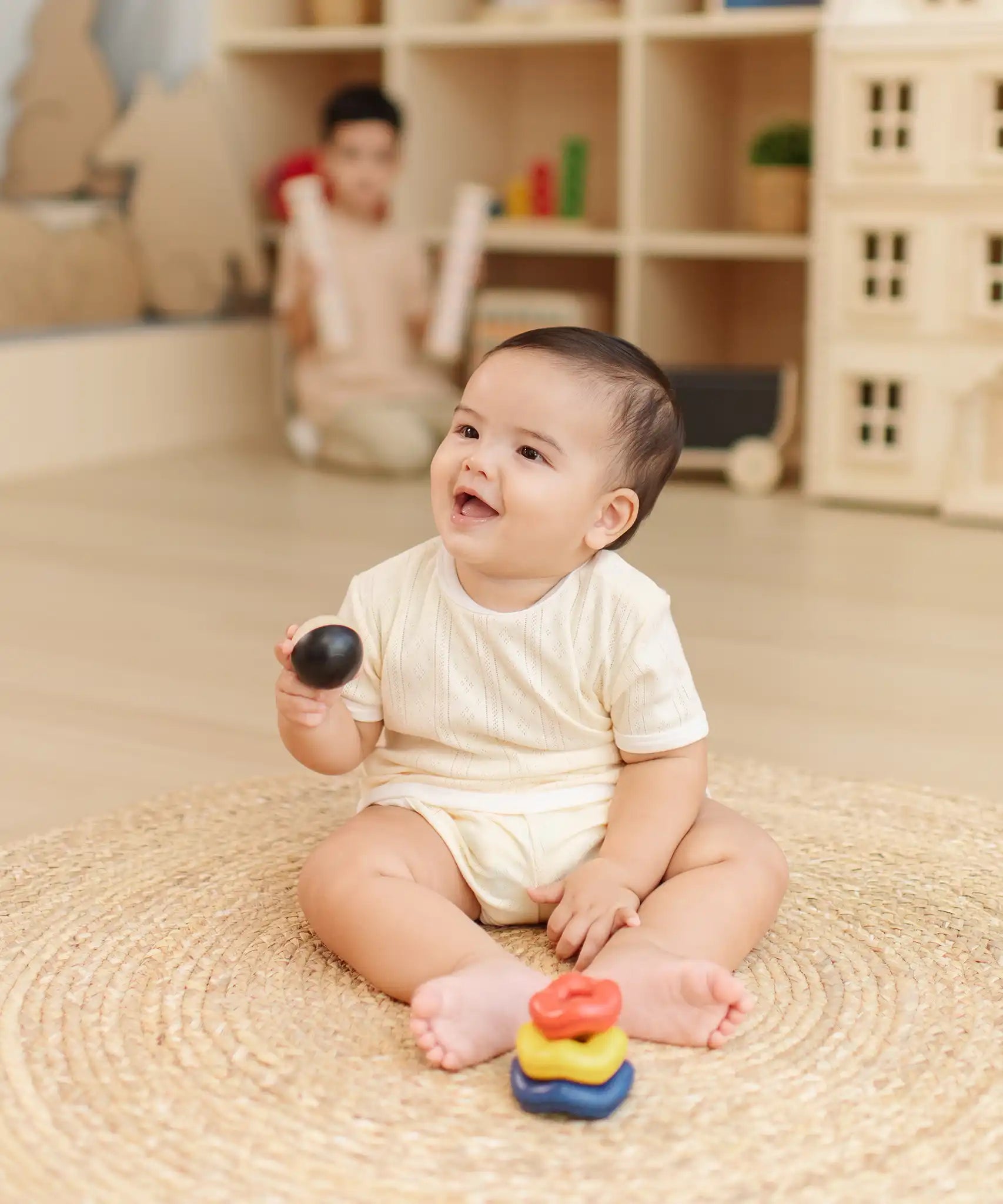 Baby playing with the PlanToys ball and wave stacker wooden baby stacking toy lifting the ball from the stack.