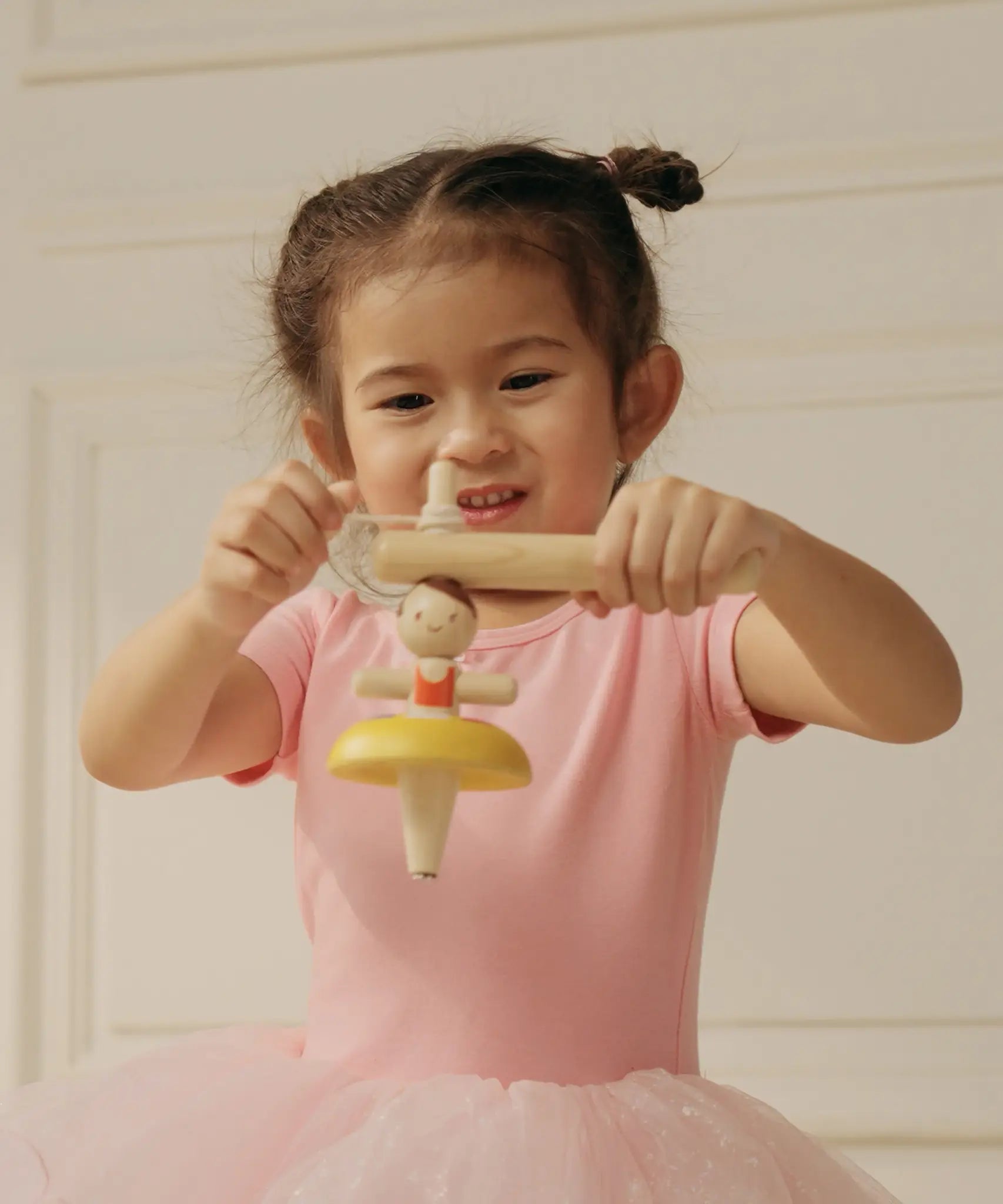 Child threading the string on the handle ready to spin the PlanToys ballerina spinning top
