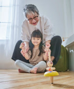 Child and grandmother playing with the PlanToys ballet spinning top on the floor 