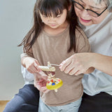 Grandmother and child threading the string on the handle of the Plantoys ballet spinning top 