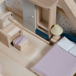 A close up of the PlanToys Bedroom Dolls House Furniture set in a wooden dolls house. 
