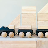 PlanToys black wooden classic toy train placed on natural wooden blocks.