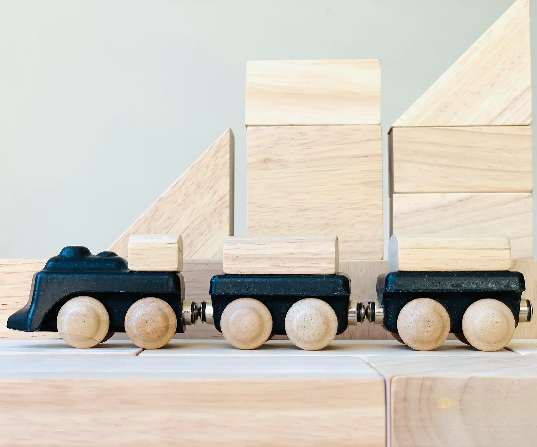 PlanToys black wooden classic toy train placed on natural wooden blocks.
