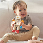 A child holding on to a Plan Toys Build a Robot toy with a smile on both their faces. 