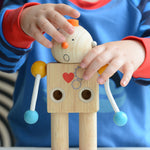 A child placing the round head with a shocked expression on the PlanToys Build a Robot. 