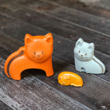 The three cat figures from the PlanToys Cat Puzzle on a wooden surface.